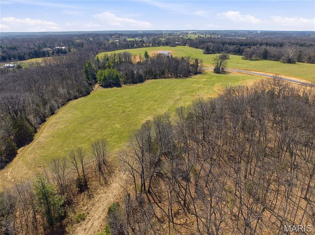 Aerial view of open meadow and wooded hillside at The Summit at Penelope Valley