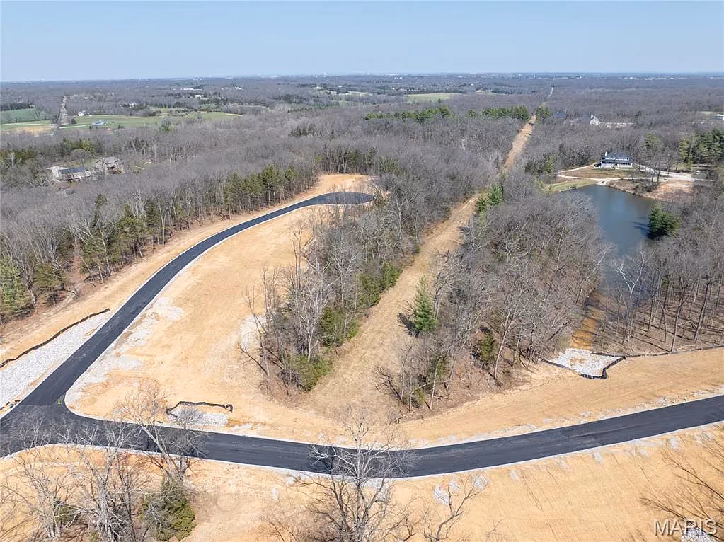 Road junction with a pond and wooded lots in early spring