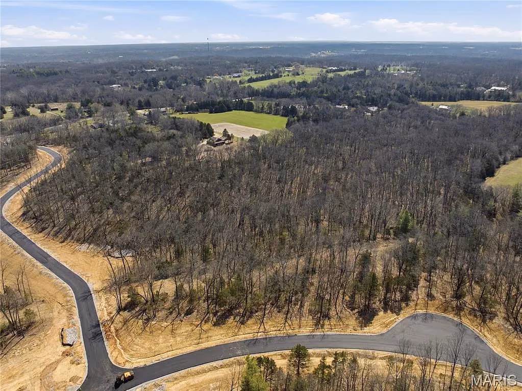 Community road climbing through woods with farmland views
